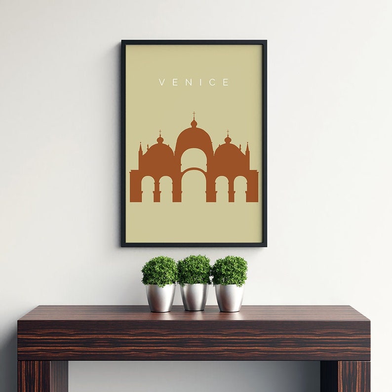 May include: A minimalist poster with a beige background and a black frame. The poster features a brown silhouette of a building with multiple domes, and the word "VENICE" in white text at the top.
