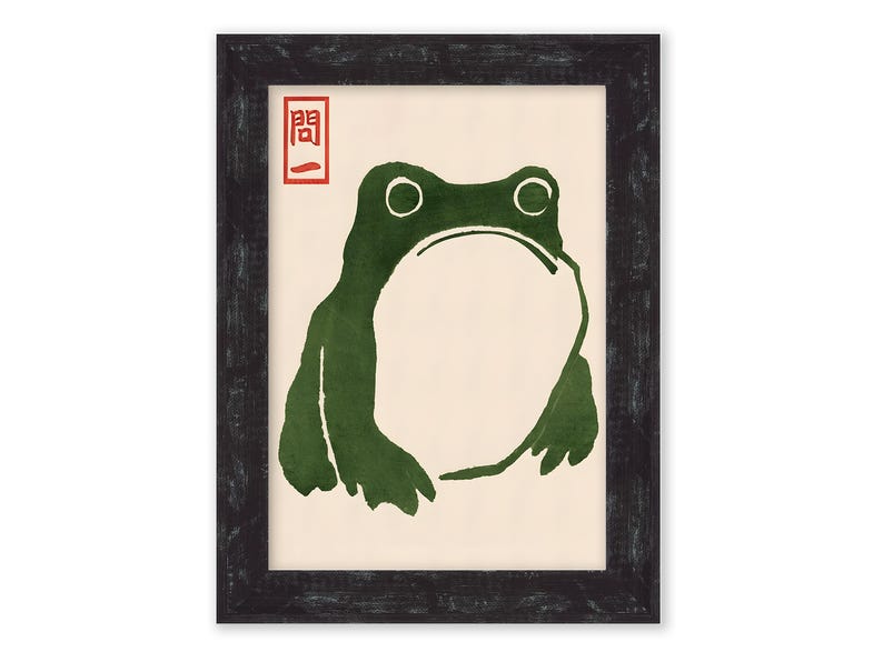 May include: A framed print of a green frog with a white background. The Japanese character "開" is printed in red in the top left corner of the print.