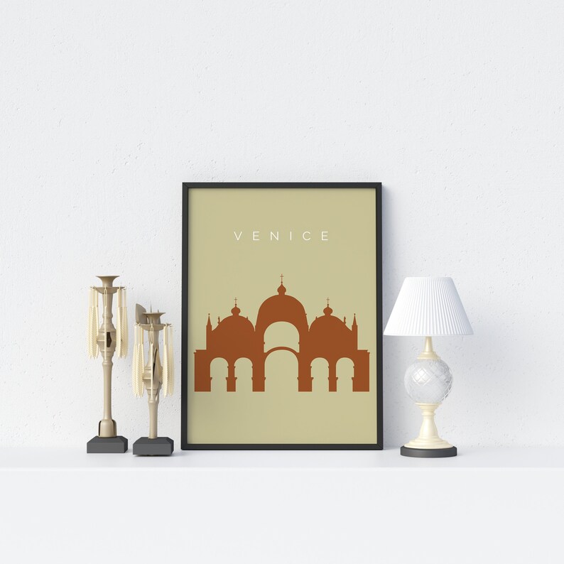 May include: A framed print with a beige background and the word "VENICE" in white text. The print features a brown silhouette of a building with multiple domes.