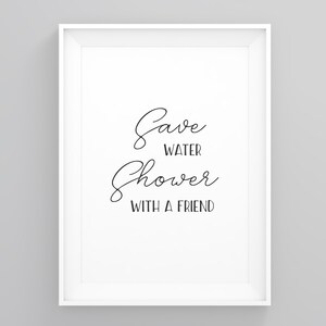May include: A framed print with the text "Save WATER Shower WITH A FRIEND" in a cursive font. The print is in a white frame and is displayed against a gray background. The artwork is a humorous bathroom decoration.
