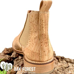 Puede incluir: Un par de botines de corcho con suela de cuero marr&oacute;n. Las botas tienen un dise&ntilde;o de f&aacute;cil calce y un sutil detalle de costura alrededor del borde superior. El nombre de la marca "OAK FOREST BEST OF NATURE" est&aacute; impreso en la suela.