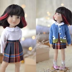 May include: A doll with black hair with red streaks wearing a white shirt, a plaid skirt, and a blue cardigan with a white sheep design.