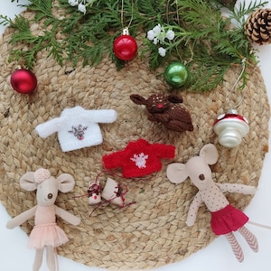 May include: A set of miniature Christmas decorations including two knitted sweaters with reindeer designs, a brown reindeer figurine, two mouse figurines, one wearing a pink tutu and the other wearing a red skirt with white polka dots, and a red and white mushroom ornament.