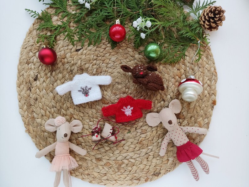 May include: A set of miniature Christmas decorations including two knitted sweaters with reindeer designs, a brown reindeer figurine, two mouse figurines, one wearing a pink tutu and the other wearing a red skirt with white polka dots, and a red and white mushroom ornament.