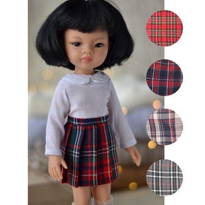 May include: A doll wearing a white collared shirt and a red, black, and white plaid skirt. The doll has black hair and brown eyes. The image also shows different plaid patterns in circles.