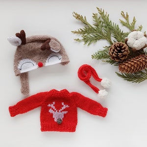 May include: A knitted reindeer hat with a red nose and white eyes, a red knitted sweater with a reindeer design, and a red knitted scarf with white pom-poms.