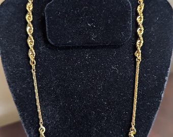 May include: A gold chain necklace with a rope chain design. The chain is displayed on a black velvet bust form.
