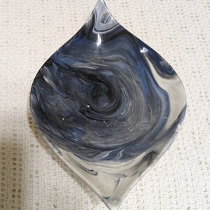 Op de afbeelding: Een witte, blauwe en zwarte gemarmerde keramische schaal in de vorm van een traan.