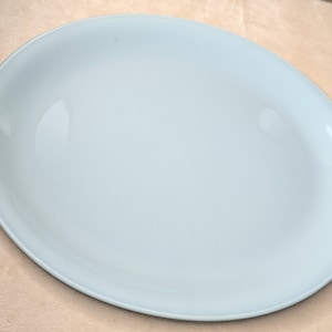 Puede incluir: Un plato ovalado para servir de color azul claro. El plato es liso y tiene un acabado brillante.