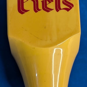 May include: A yellow plastic beer tap handle with the word "Piels" in red lettering.