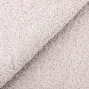 Op de afbeelding: Close-up van een lichtgrijze stof met een getextureerd, noppig oppervlak. De stof is diagonaal gevouwen, waardoor de textuur en diepte van het materiaal zichtbaar worden. De stof lijkt zacht en pluche, geschikt voor diverse textielprojecten.