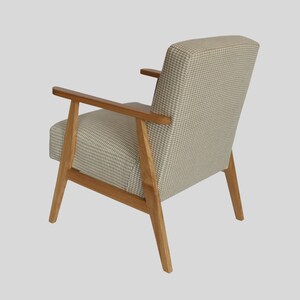 Puede incluir: Un sill&oacute;n beige con tapicer&iacute;a de cuadros y patas y brazos de madera.
