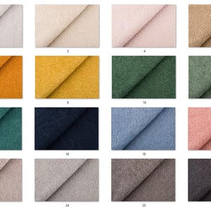 Op de afbeelding: Een verzameling stoffen stalen in verschillende kleuren, waaronder gebroken wit, beige, roze en tinten groen, blauw en bruin. De stalen zijn gerangschikt in een raster, met de verschillende texturen en tinten die beschikbaar zijn voor bekledings- of textielprojecten.