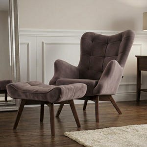 May include: A taupe-coloured wingback armchair and matching ottoman featuring a tufted backrest and seat cushion. Both pieces are supported by four dark brown wooden legs angled outward, providing a stable base for the upholstered furniture set.