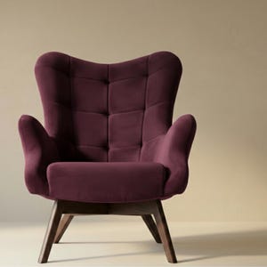 May include: A deep plum-coloured armchair featuring a high, tufted backrest with a grid pattern, curved armrests, and a cushioned seat. The chair is supported by four angled, dark brown wooden legs that provide a stable base for the structure.