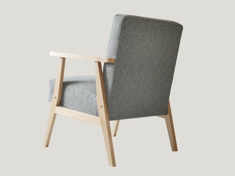 May include: A gray upholstered armchair with wooden legs and arms. The chair has a simple, modern design.