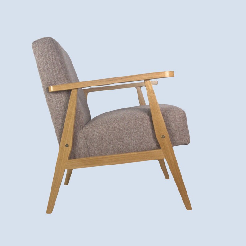 May include: A brown armchair with wooden legs and arms. The chair has a light brown fabric upholstery.