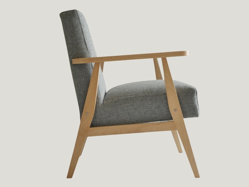May include: A gray upholstered armchair with a wooden frame. The chair has a high back and a wide seat. The wooden frame is light brown and has a simple design.