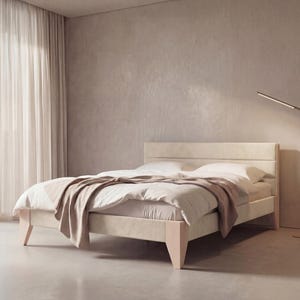 Könnte beinhalten: Ein beige gepolstertes Bett mit passendem Kopfteil und hellfarbigen Holzbeinen. Das Bett ist mit weißer Bettwäsche und einer braunen Decke ausgestattet. Eine moderne Stehlampe und transparente Vorhänge sind ebenfalls zu sehen.
