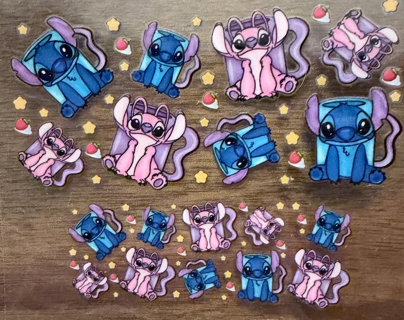 May include: A collection of colorful stickers featuring the characters Stitch and Angel from the animated movie Lilo & Stitch. The stickers are in various poses and surrounded by star and strawberry-shaped accents.