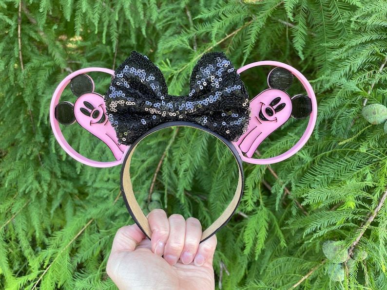 May include: Pink Mickey Mouse ears with a black sequin bow and a ghost design on each ear.