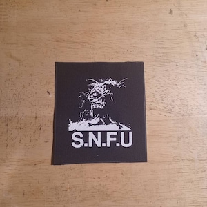 Peut inclure: Patch noir et blanc avec un graphique de tête de monstre et le texte "S.N.F.U."