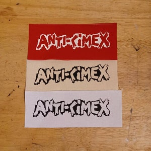 Op de afbeelding: Drie rechthoekige patches met de tekst "ANTI-CIMEX" in een vet, gestileerd lettertype. De bovenste patch is rood, de middelste is beige en de onderste is wit. De patches zijn verticaal gerangschikt.