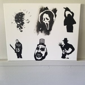 Può includere: Arte a stencil in bianco e nero su una tela bianca con personaggi iconici di film horror. I personaggi includono Jason Voorhees di Venerdì 13, Ghostface di Scream, Leatherface di Non aprite quella porta, e Michael Myers di Halloween.