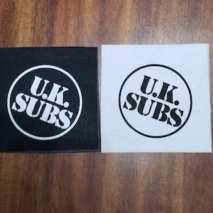 May include: Two fabric patches with the text "U.K. SUBS" in a circle. One patch is black with white text, and the other is white with black text.