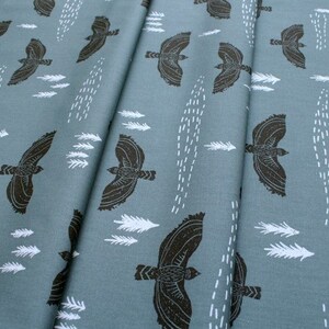 May include: A teal fabric with a repeating pattern of black birds flying and white stylized feathers. The fabric has a subtle texture.