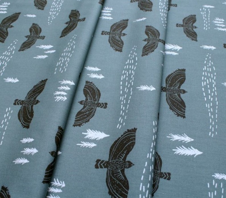 May include: A teal fabric with a repeating pattern of black birds flying and white stylized feathers. The fabric has a subtle texture.