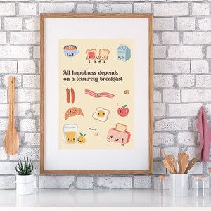 May include: A framed print with a yellow background and illustrations of breakfast foods with faces. The text reads "All happiness depends on a leisurely breakfast."