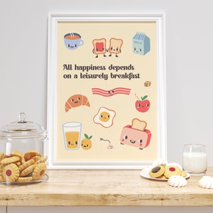 May include: A framed print with a yellow background and a quote that reads "All happiness depends on a leisurely breakfast". The print features cartoon illustrations of breakfast foods, including toast, milk, bacon, eggs, a croissant, an apple, a glass of orange juice, and a toaster.