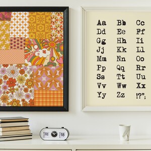 May include: Two framed prints on a white wall. The print on the left is a collage of colorful geometric and floral patterns. The print on the right is a white background with black text that reads "Aa Bb Cc Dd Ee Ff Gg Hh Ii Jj Kk Ll Mm Nn Oo Pp Qq Rr Ss Tt Uu Vv Ww Xx Yy Zz !?'".