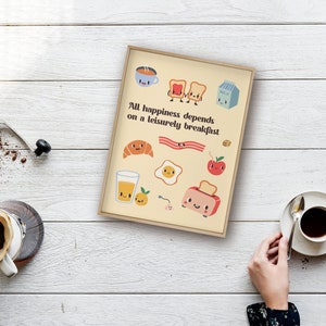 May include: A beige framed print with a yellow background and colorful cartoon illustrations of breakfast foods. The text reads "All happiness depends on a leisurely breakfast."