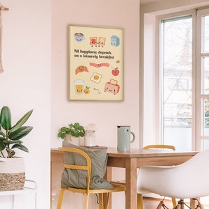 May include: A yellow and white poster with a cartoon illustration of breakfast foods with faces. The text on the poster reads "All happiness depends on a leisurely breakfast."