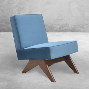 May include: A blue upholstered chair with a wooden frame and angled legs. The chair is sitting on a concrete floor.