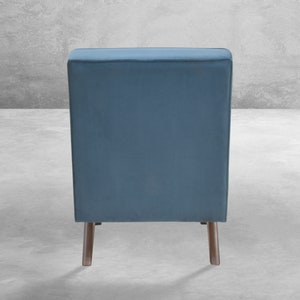 May include: A blue velvet armchair with wooden legs. The chair is shown from the back.