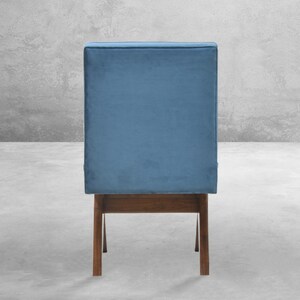 May include: A blue velvet chair with a wooden frame. The chair has a simple design with a rectangular seat and back.
