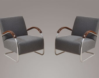 May include: Two gray upholstered armchairs with chrome frames and wooden arms. The chairs have a modern design and are perfect for a living room or office.