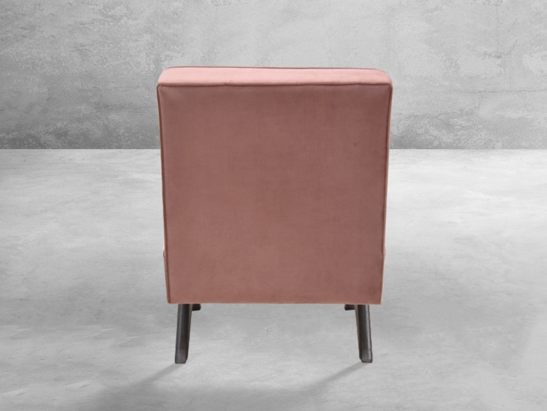 May include: A dusty rose velvet armchair with black legs. The chair is shown from the back.