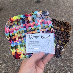 May include: A pair of woven coasters in vibrant colors, including red, yellow, blue, and green. One coaster has a rainbow pattern, and the other is brown and black. A small card with the text "Thank You!" is included.