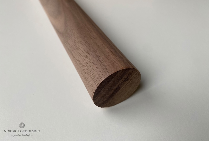 Puede incluir: Primer plano de una varilla de madera redonda hecha de madera de nogal. La madera tiene un color marr&oacute;n intenso y un acabado liso y pulido.