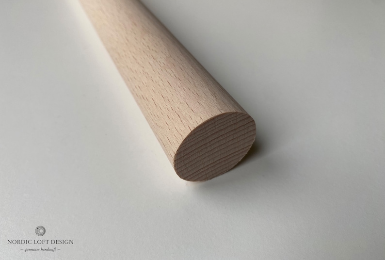 Puede incluir: Primer plano de una varilla de madera de color marr&oacute;n claro con un extremo redondeado. La varilla es lisa y tiene una veta de madera natural.