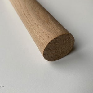 Puede incluir: Primer plano de una varilla de madera redonda. La madera tiene un color marr&oacute;n claro natural y un acabado liso y pulido.