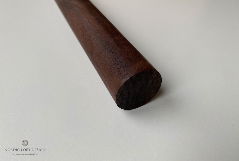 Puede incluir: Primer plano de un rodillo de madera marr&oacute;n oscuro. El rodillo es liso y tiene un extremo redondeado.