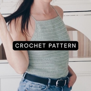 K&ouml;nnte beinhalten: Ein helles, salbeigr&uuml;nes H&auml;kel-Neckholder-Top mit quadratischem Ausschnitt und d&uuml;nnen Tr&auml;gern, das den Text CROCHET PATTERN in einem schwarzen rechteckigen Feld zeigt. Das Kleidungsst&uuml;ck wird mit einer blauen Jeans und einem schwarzen Lederg&uuml;rtel kombiniert.