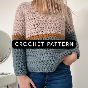 May include: A long-sleeve crochet sweater featuring a color-blocked design with a light pink upper section, a thin mustard yellow stripe, and a blue lower section. The text CROCHET PATTERN is displayed in white letters on a black rectangular background.