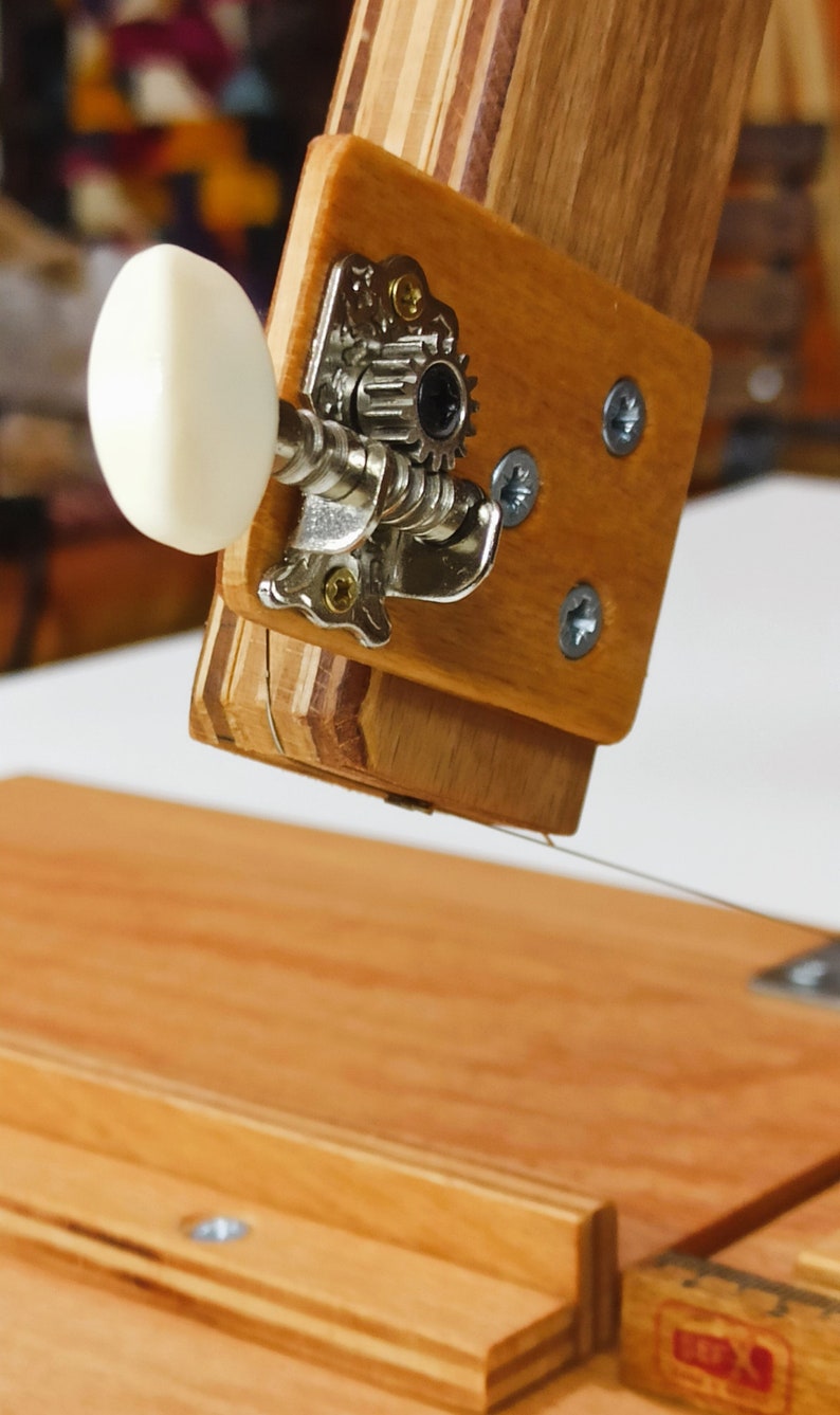 Pu&ograve; includere: Primo piano di un leggio in legno con un pirolo di accordatura argentato e una manopola bianca. Il leggio &egrave; fatto di pi&ugrave; strati di legno.