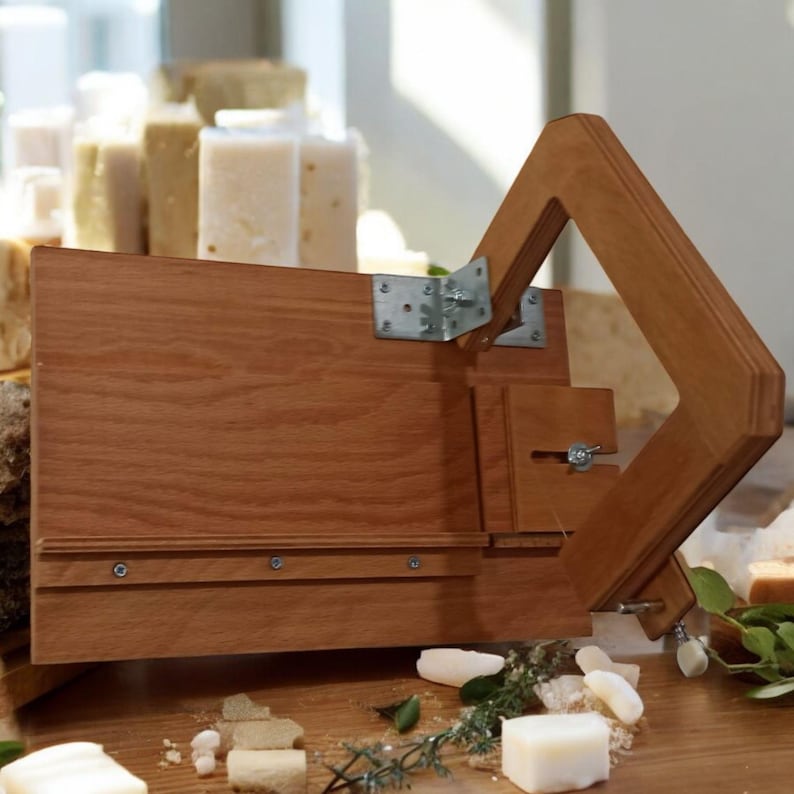 Pu&ograve; includere: Un tagliapanni per sapone in legno con una maniglia a cerniera e una staffa in metallo. Il tagliapanni &egrave; realizzato in legno marrone chiaro e ha una superficie liscia. La maniglia &egrave; realizzata in legno marrone scuro e ha una superficie ruvida. Il tagliapanni &egrave; progettato per tagliare le barre di sapone in pezzi pi&ugrave; piccoli.